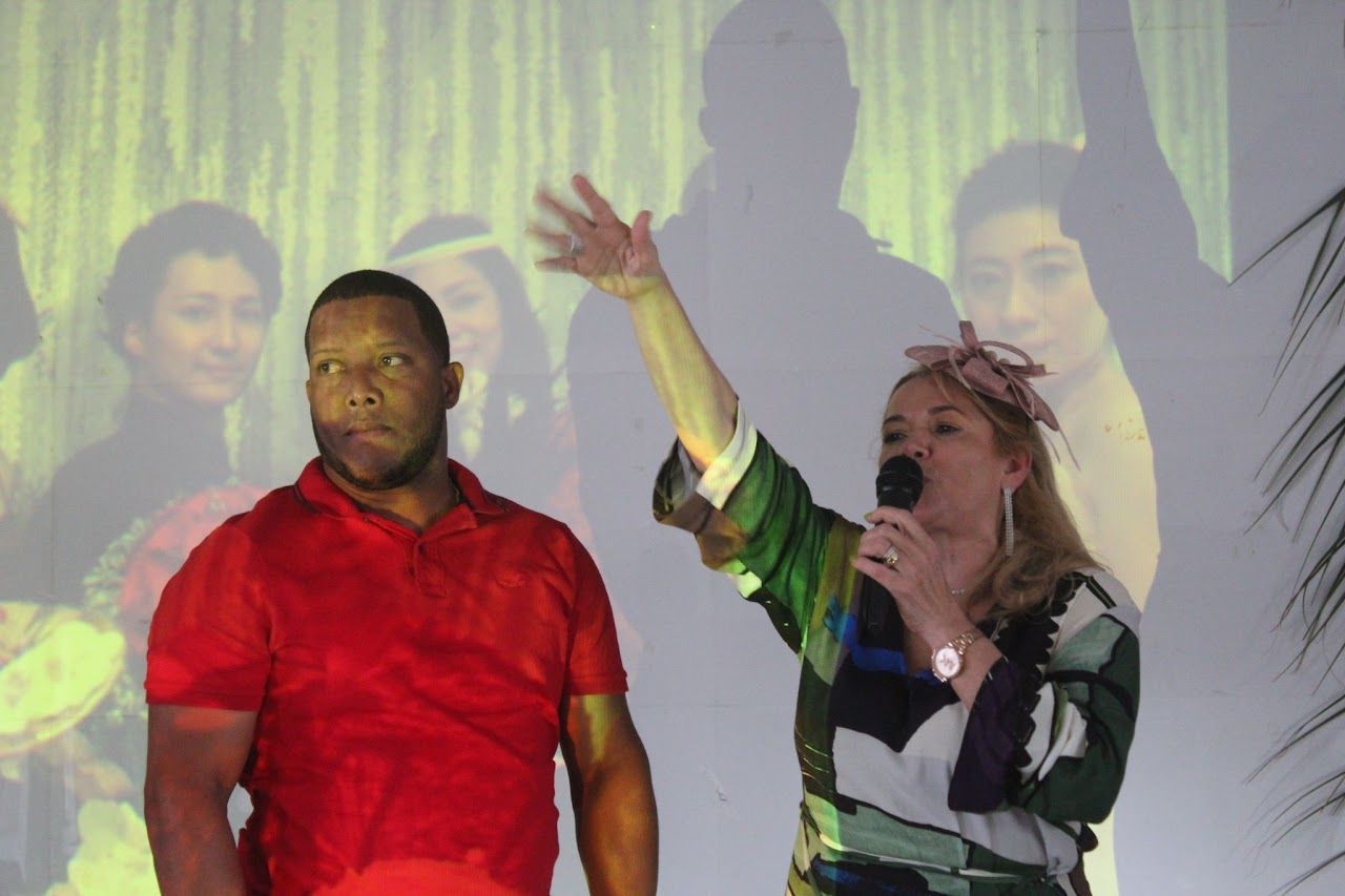 A man in a red shirt is standing next to a woman holding a microphone.