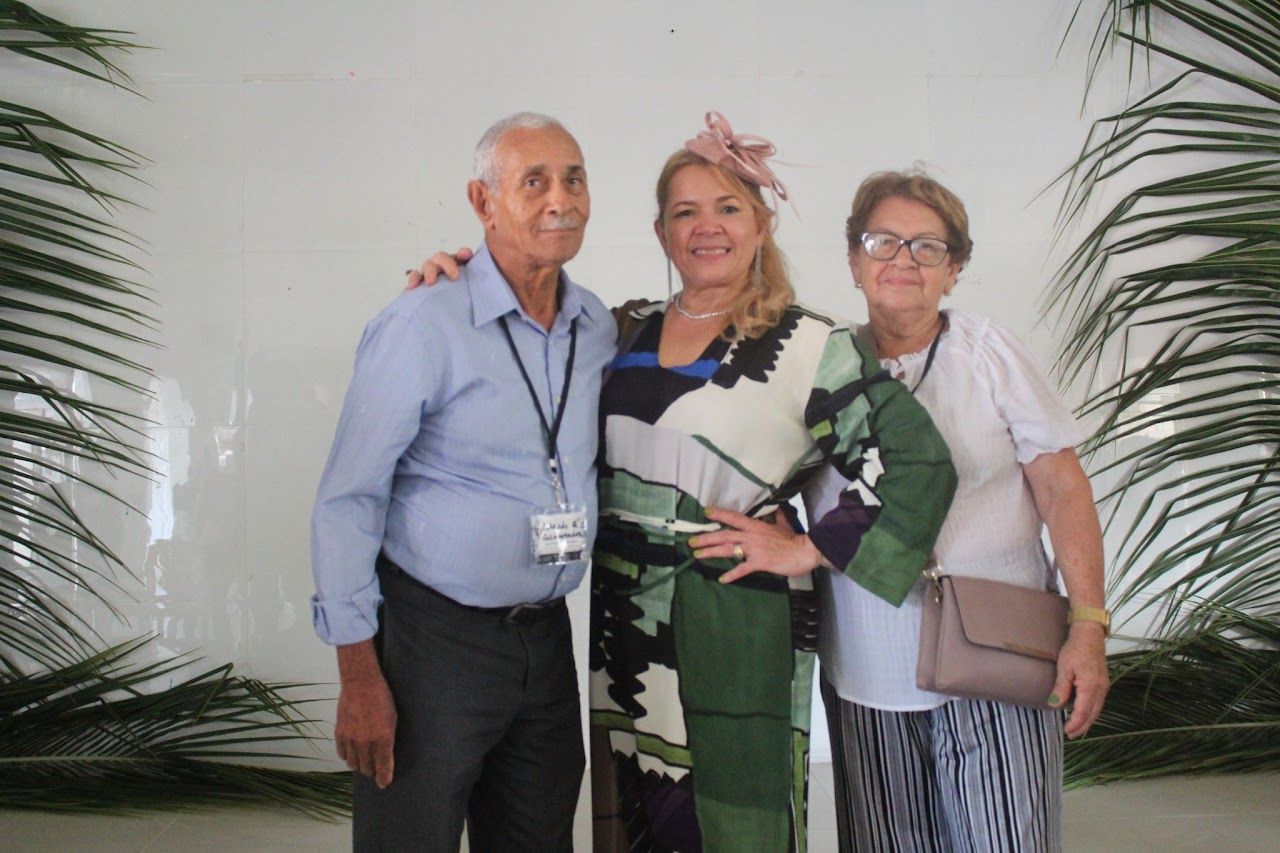 Three people posing for a picture in front of palm trees