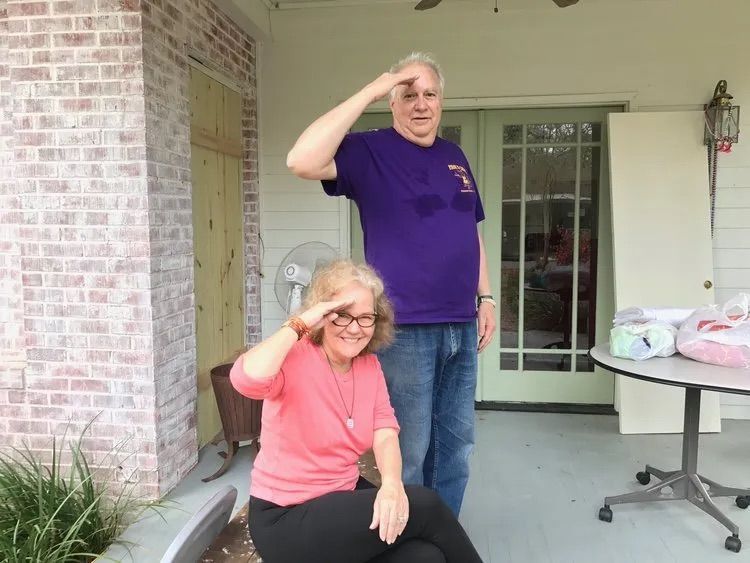 A man in a purple shirt salutes a woman in a pink shirt