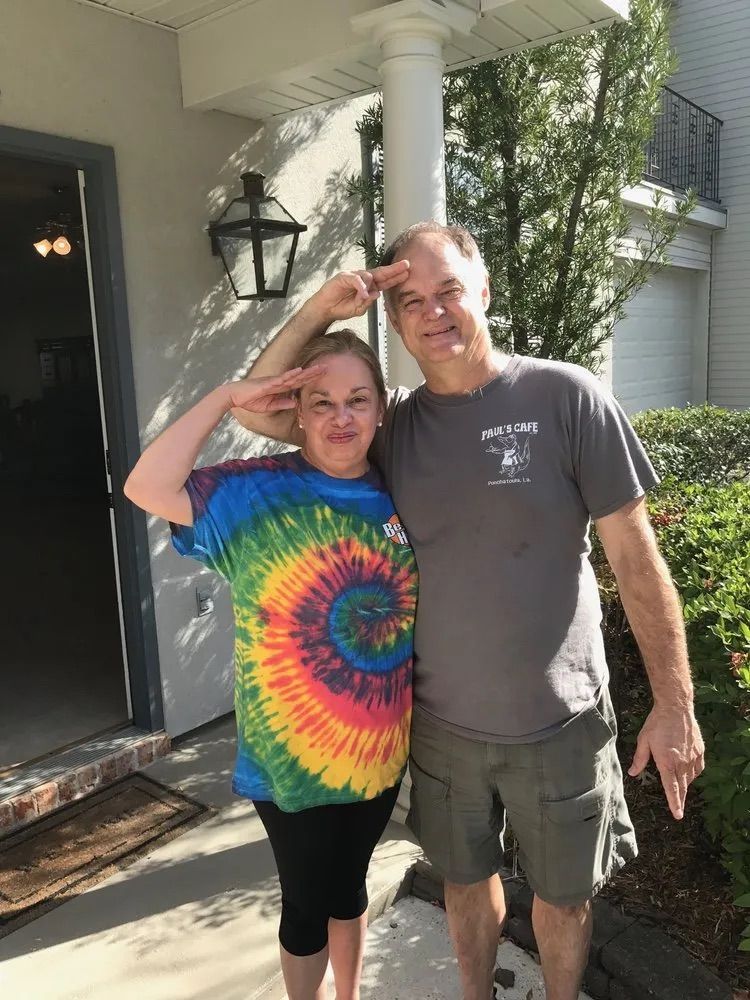 A man and a woman are posing for a picture in front of a house.