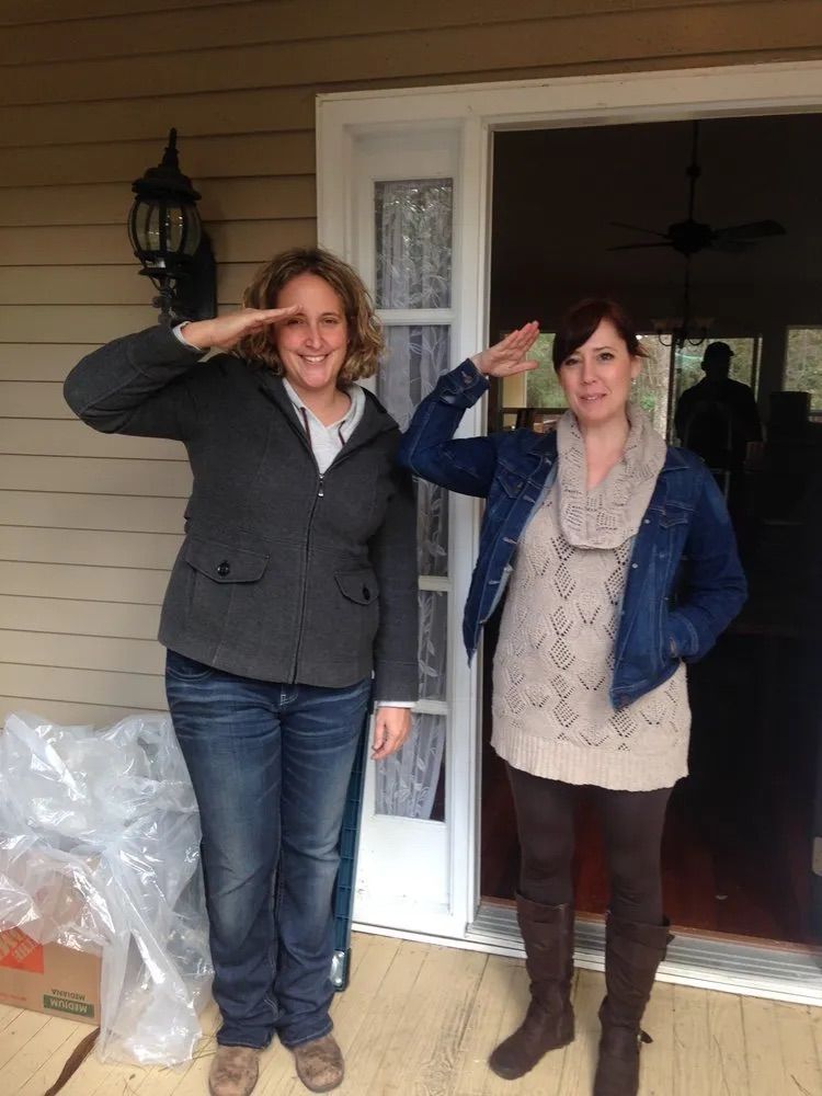 Two women are saluting in front of a house
