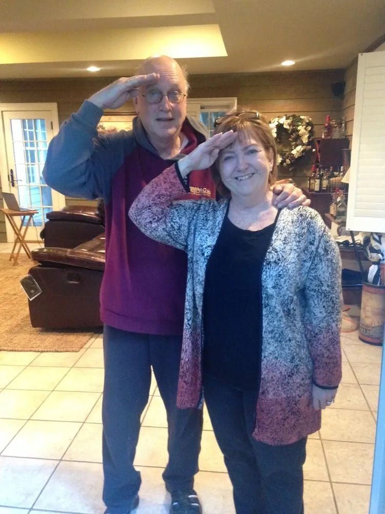A man and a woman are saluting in a living room