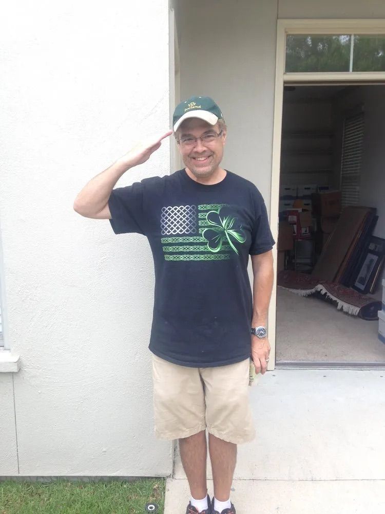 A man wearing a black shirt with an american flag on it salutes