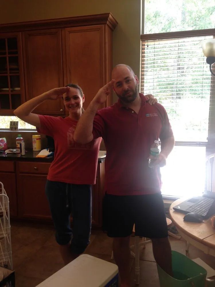 A man and a woman are posing for a picture in a kitchen