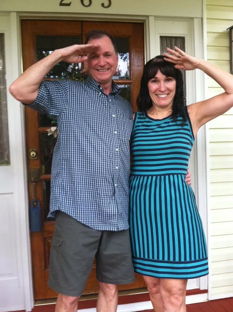 A man and a woman are posing for a picture in front of a door that says 203