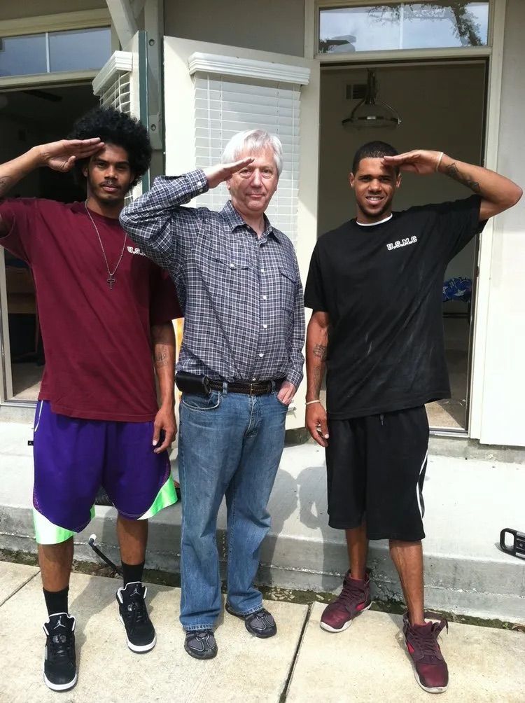 A man in a plaid shirt salutes with two other men