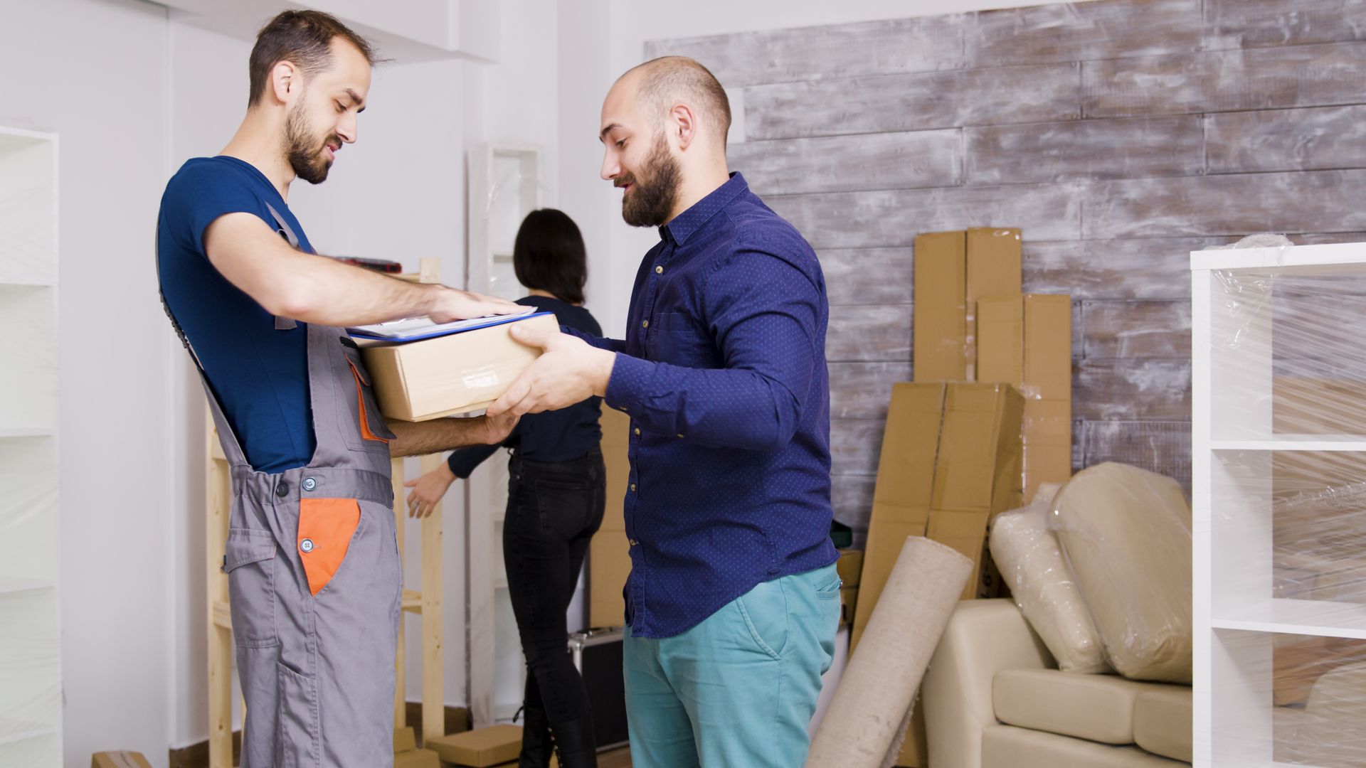 A man is giving a box to another man in a living room.