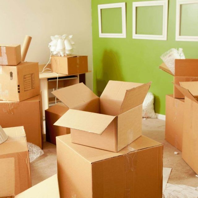 Cardboard boxes are stacked on top of each other in a room with a green wall