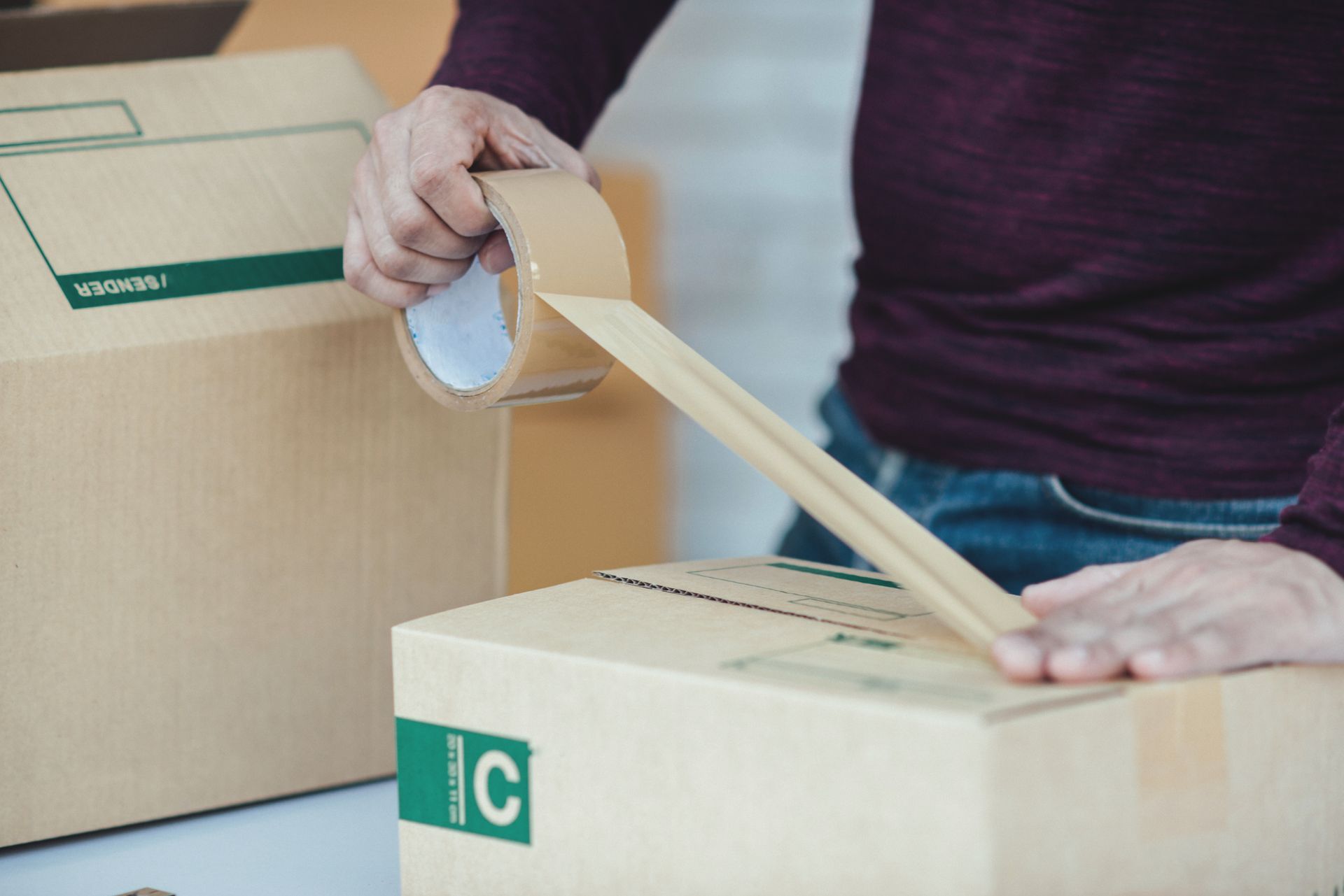 A person is wrapping a cardboard box with tape.