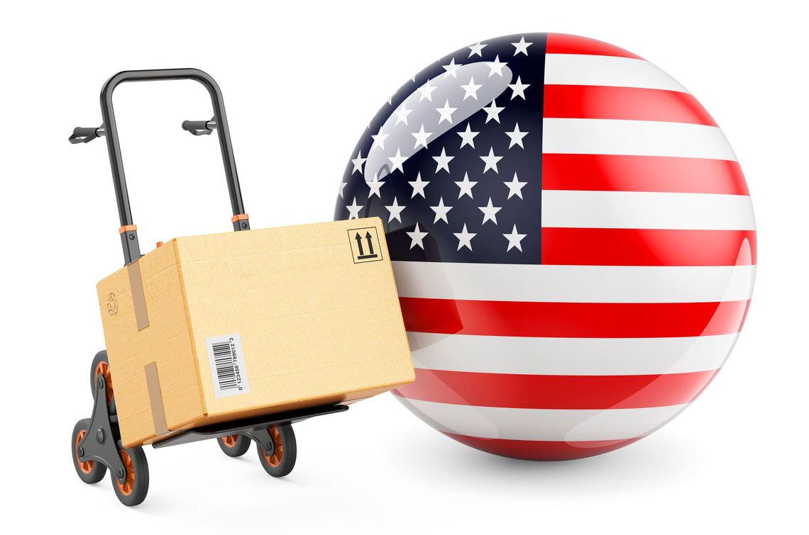A cardboard box on a dolly next to an american flag.