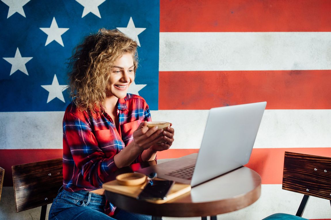 A woman is sitting at a table with a laptop and a cup of coffee.