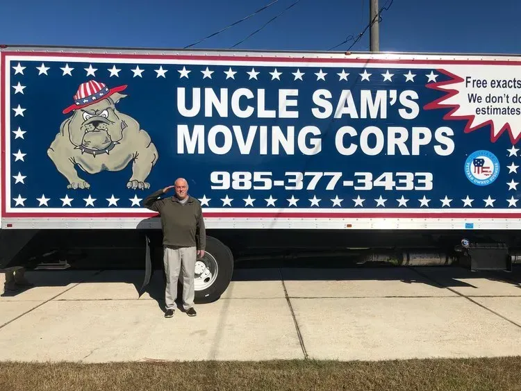 A man salutes in front of an uncle sam 's moving corps truck