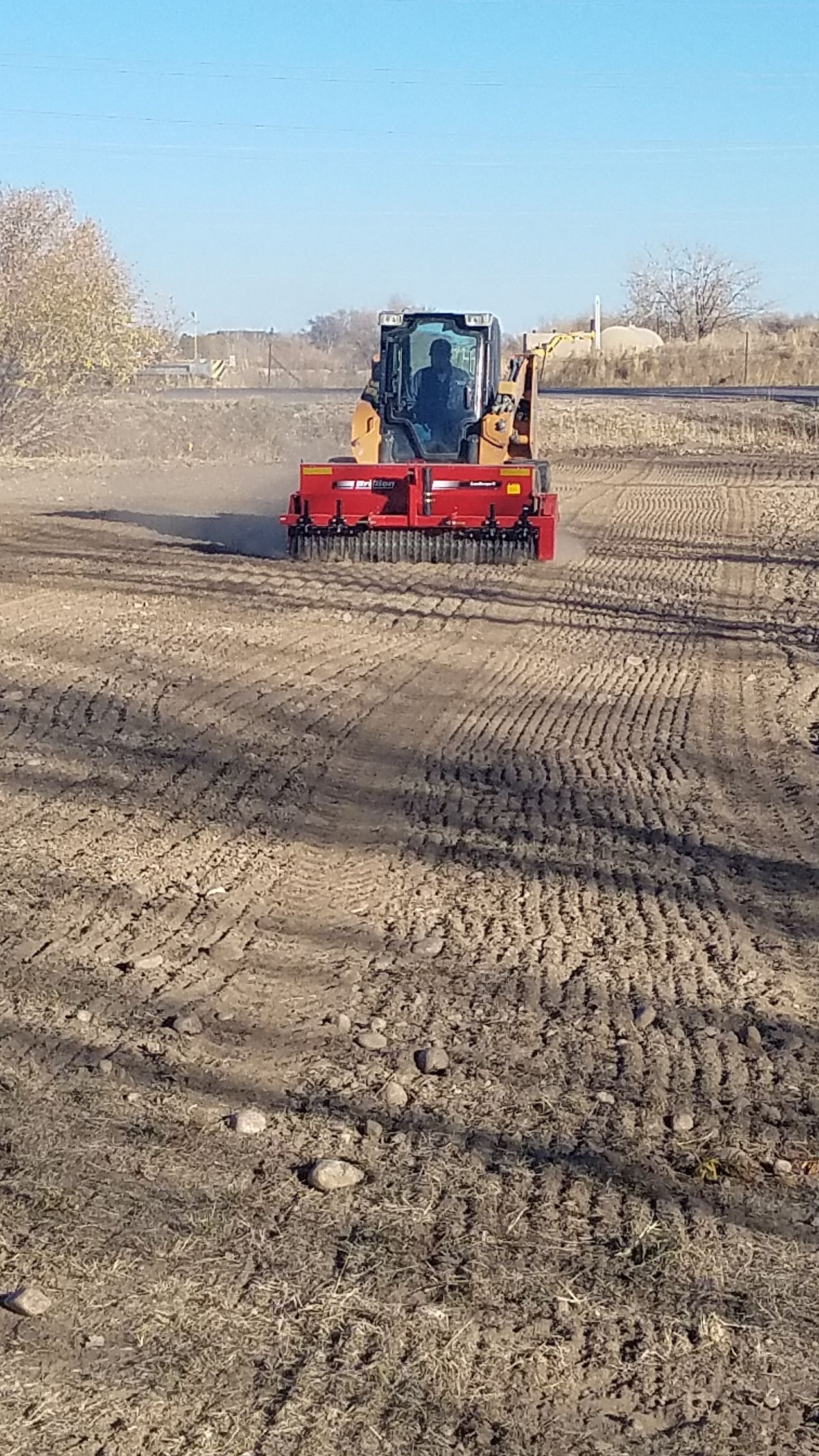 A tractor is plowing a dry field with a machine.