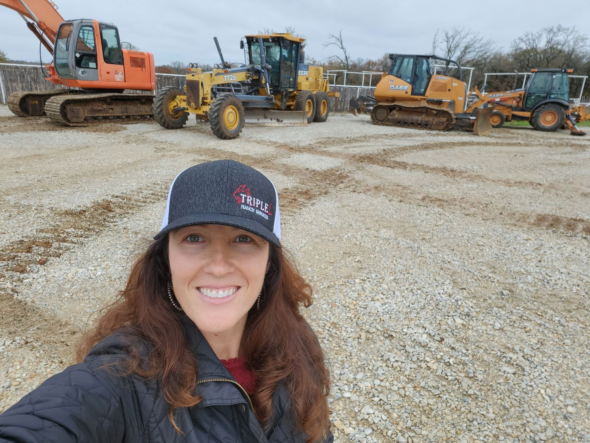 A woman is standing in front of a row of construction vehicles.