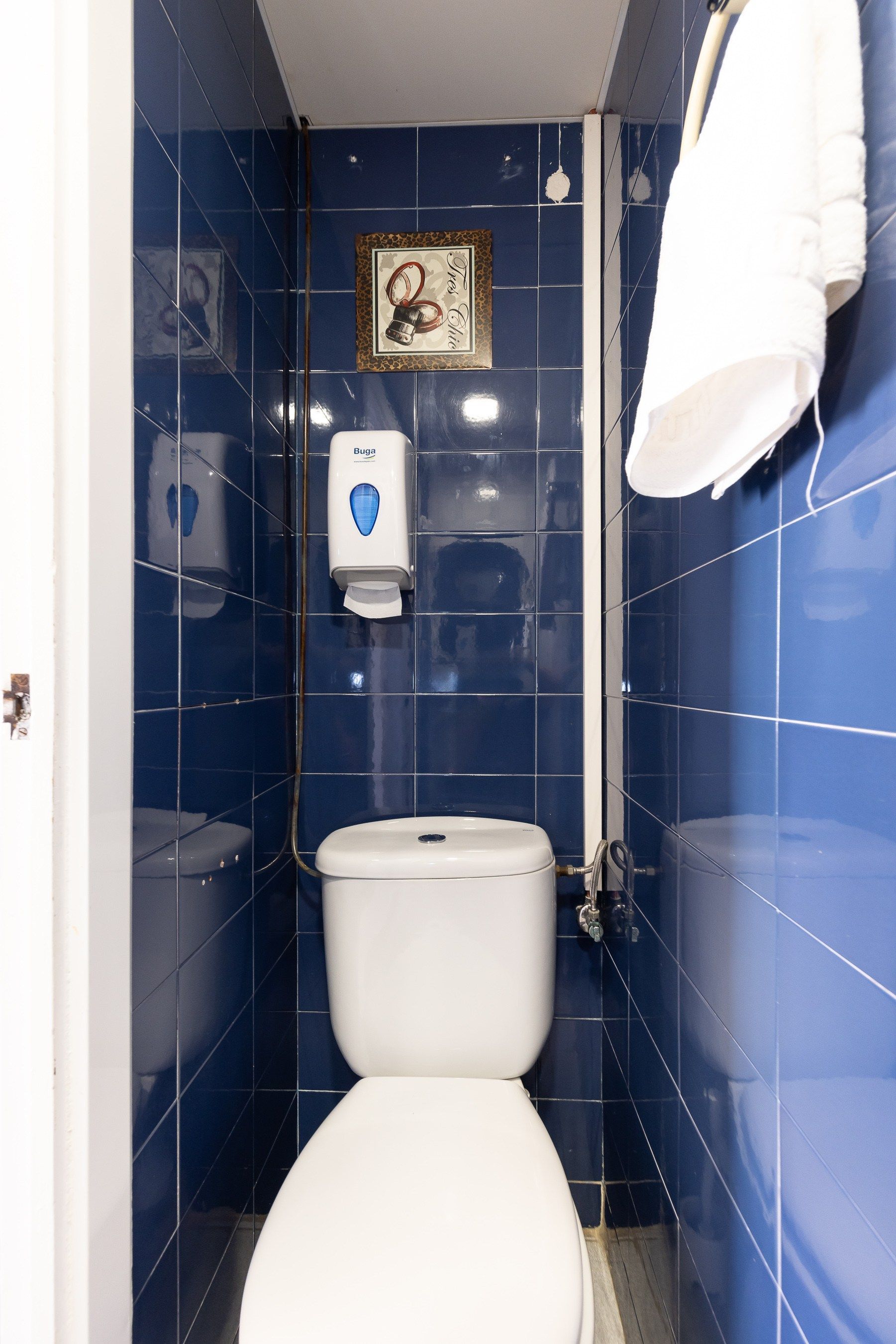 Un pequeño baño con azulejos azules y un inodoro.