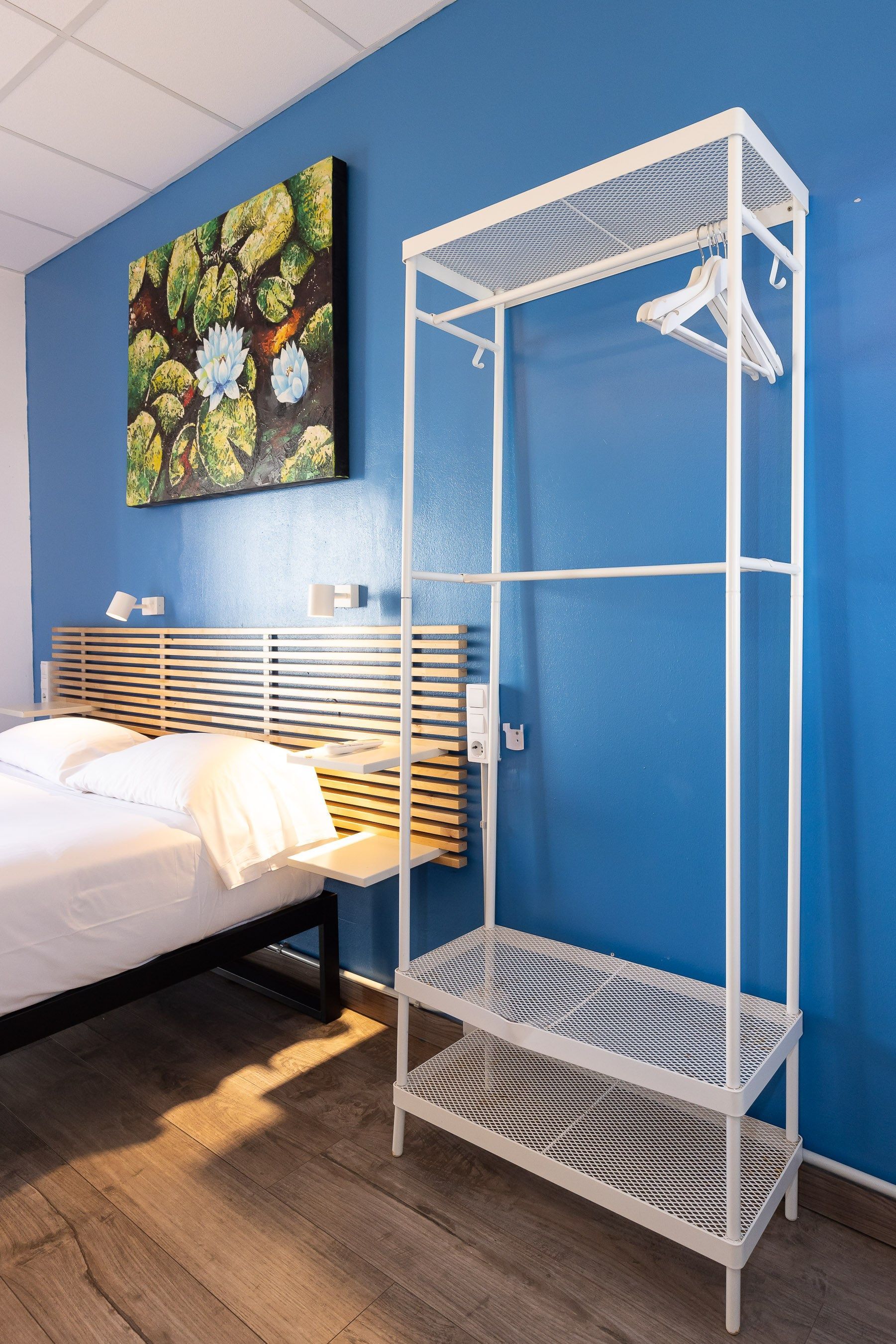Un dormitorio con una cama, un cuadro en la pared y un armario blanco.