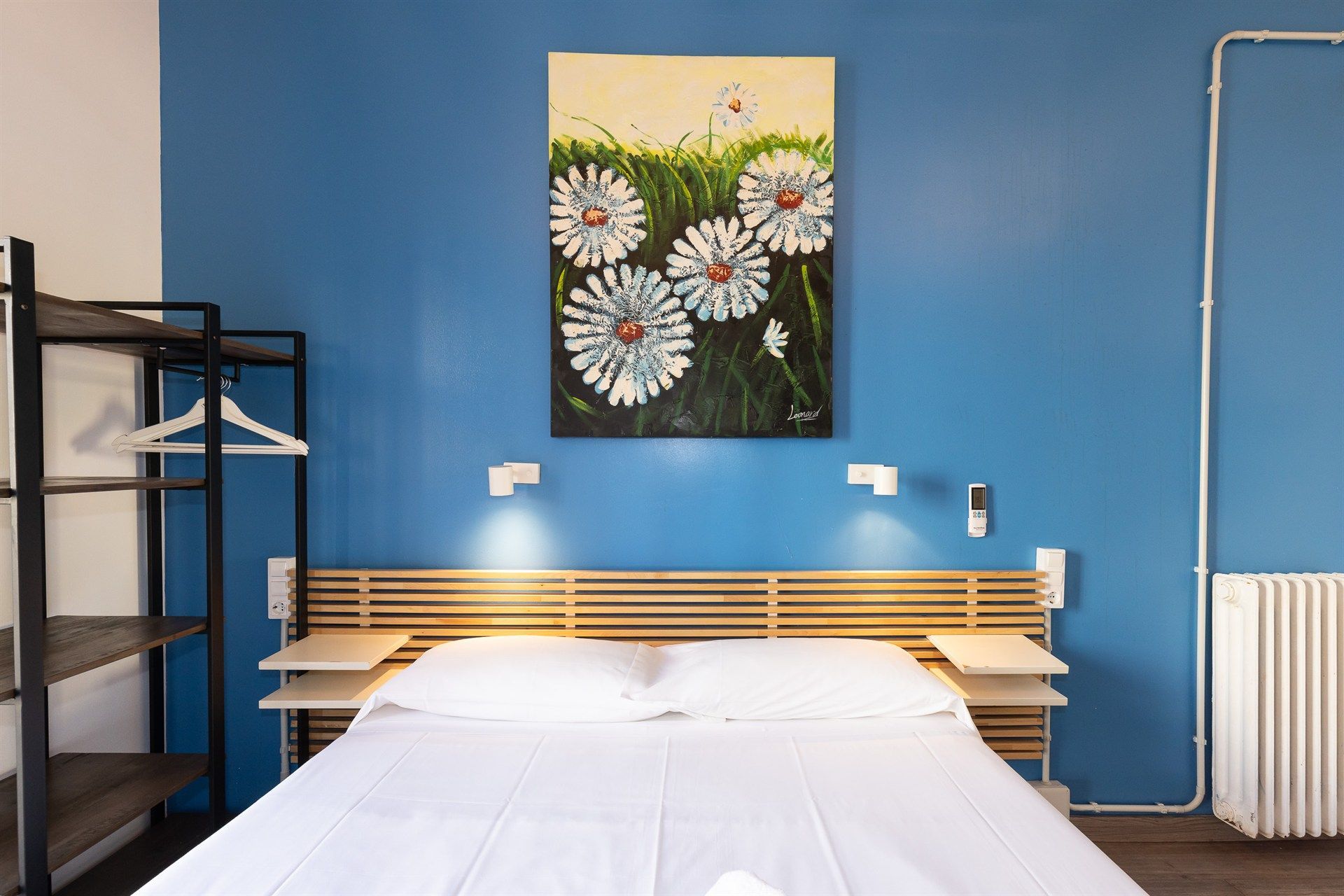 Hay un cuadro de margaritas en la pared encima de la cama.
