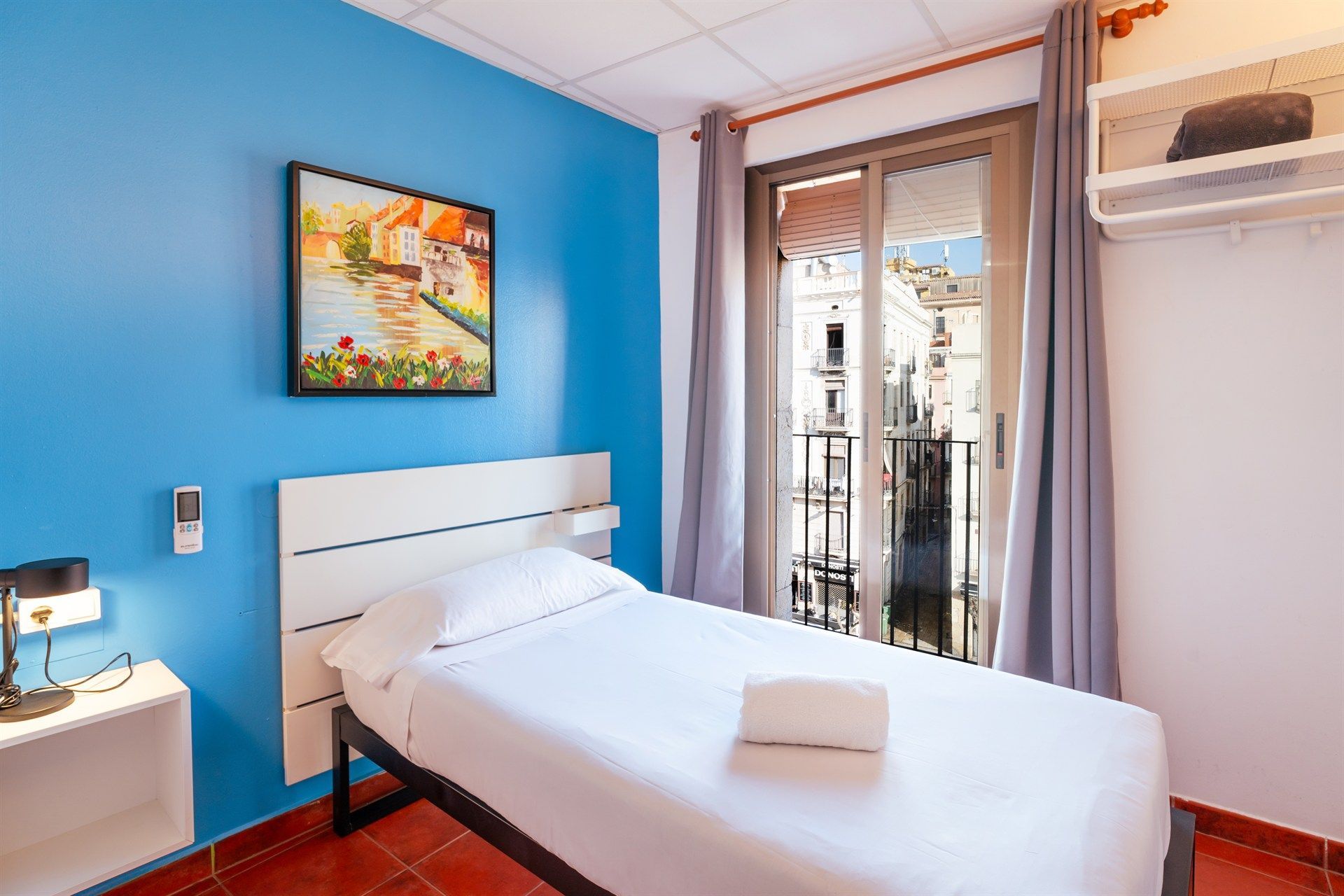 Un dormitorio con una cama individual y un cuadro en la pared.