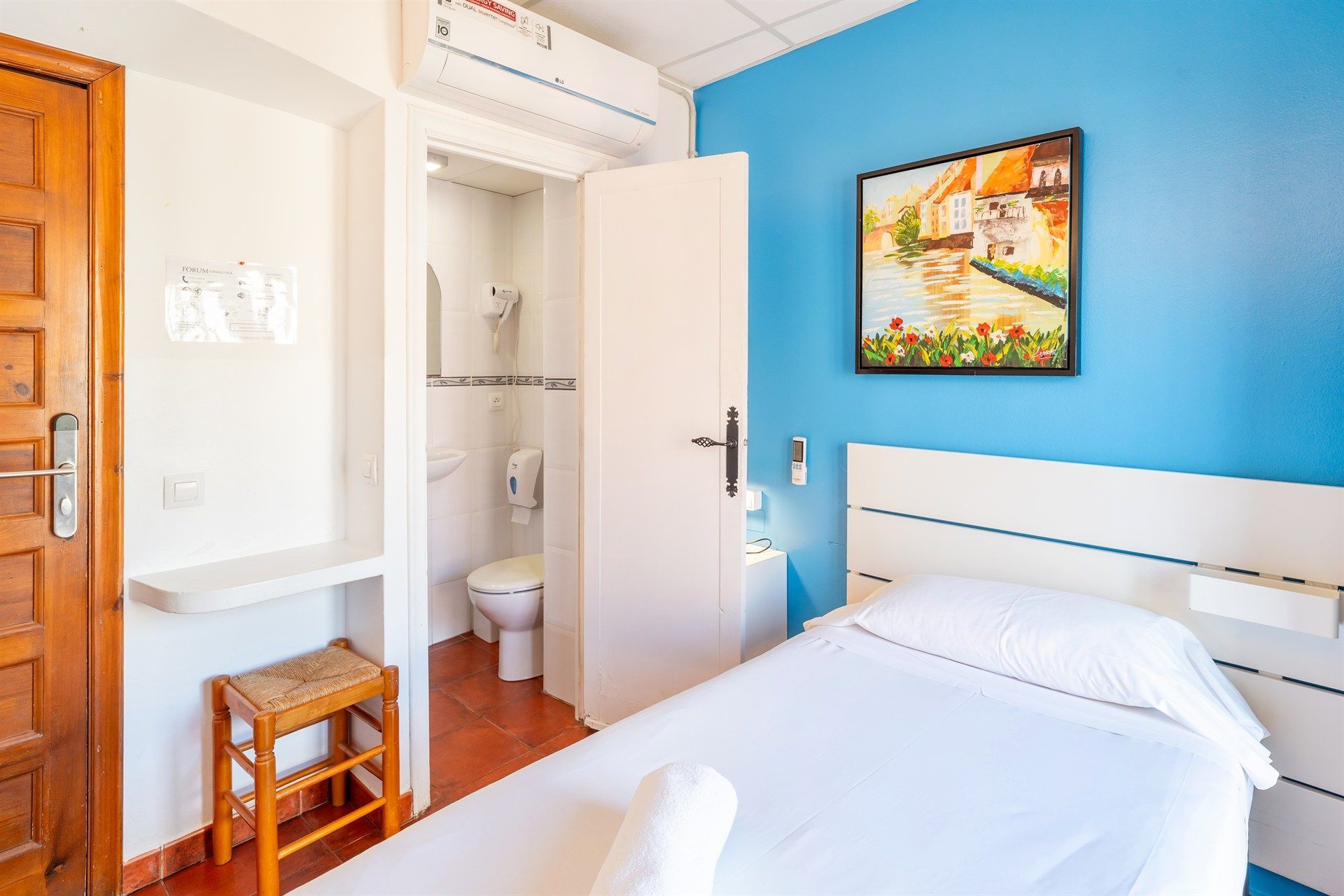Una habitación de hotel con una cama, un baño y un cuadro en la pared.