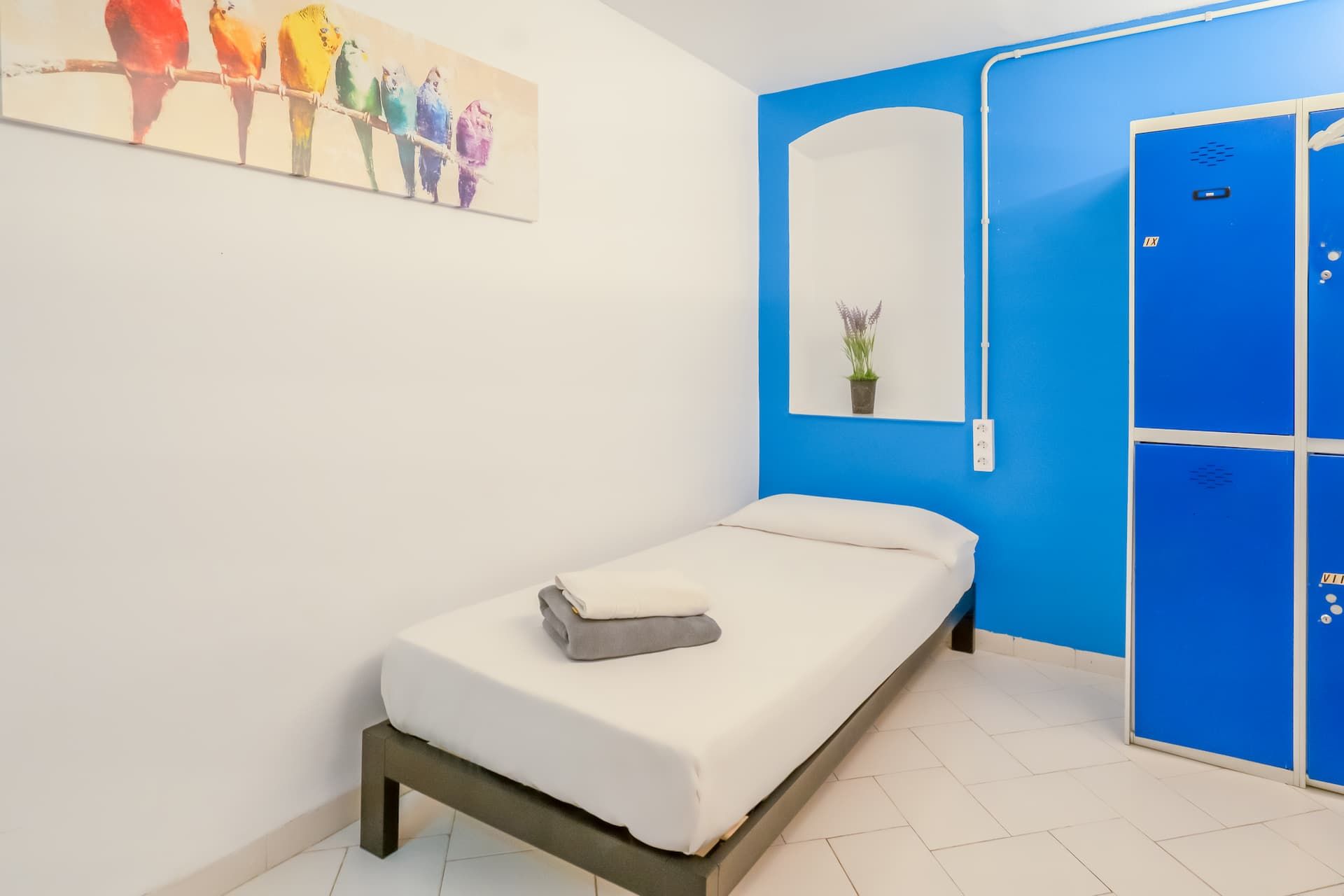 Un dormitorio con una cama individual y taquillas azules.