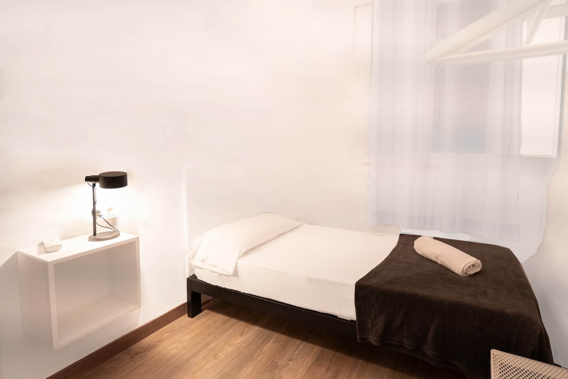 Un dormitorio con una cama individual y una lámpara en la pared.