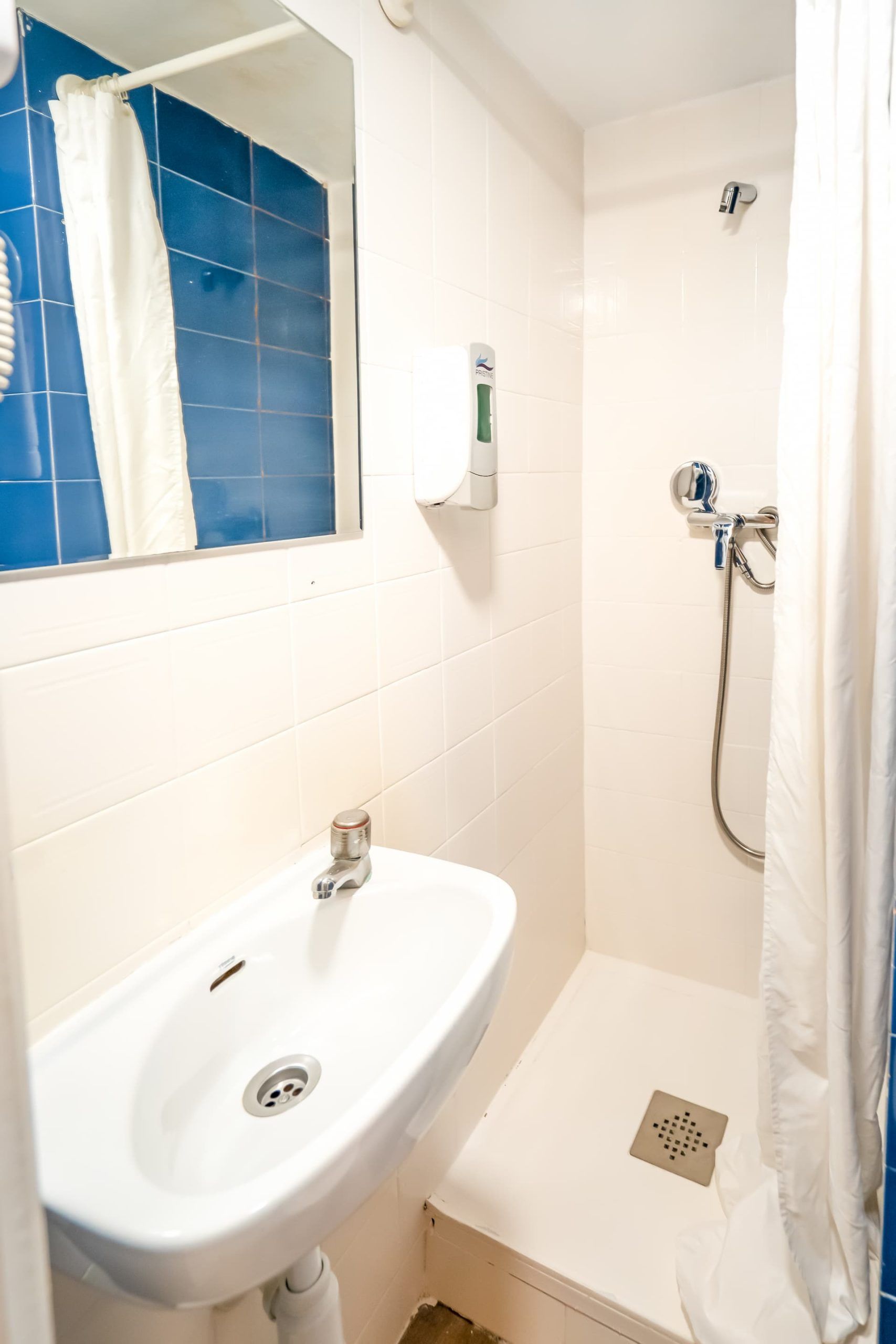 Un baño con lavabo, ducha y espejo.