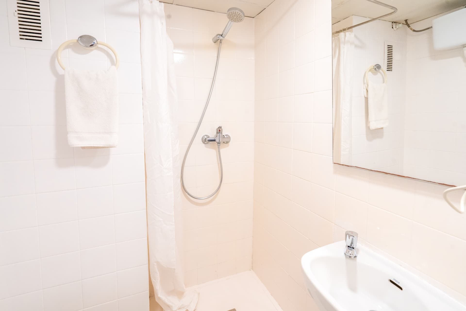Un baño con lavabo, ducha y espejo.