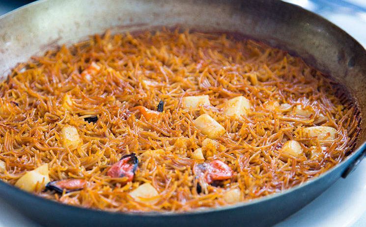 Una sartén llena de arroz y verduras sobre una mesa.