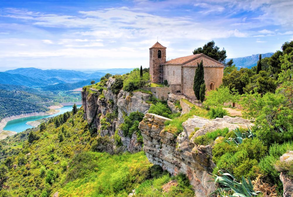 Una pequeña iglesia está situada en lo alto de un acantilado con vistas a un lago.