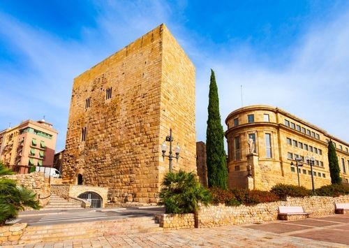 Un gran edificio de piedra con escaleras que conducen a él está al lado de un edificio más pequeño.