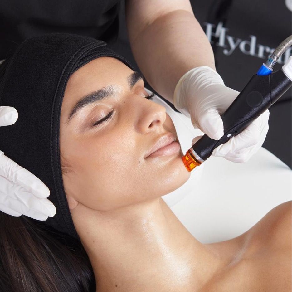 Woman receiving hydrafacial treatment in beauty salon