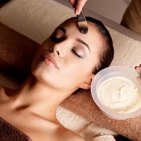 Young woman applying cosmetic white cream on her face