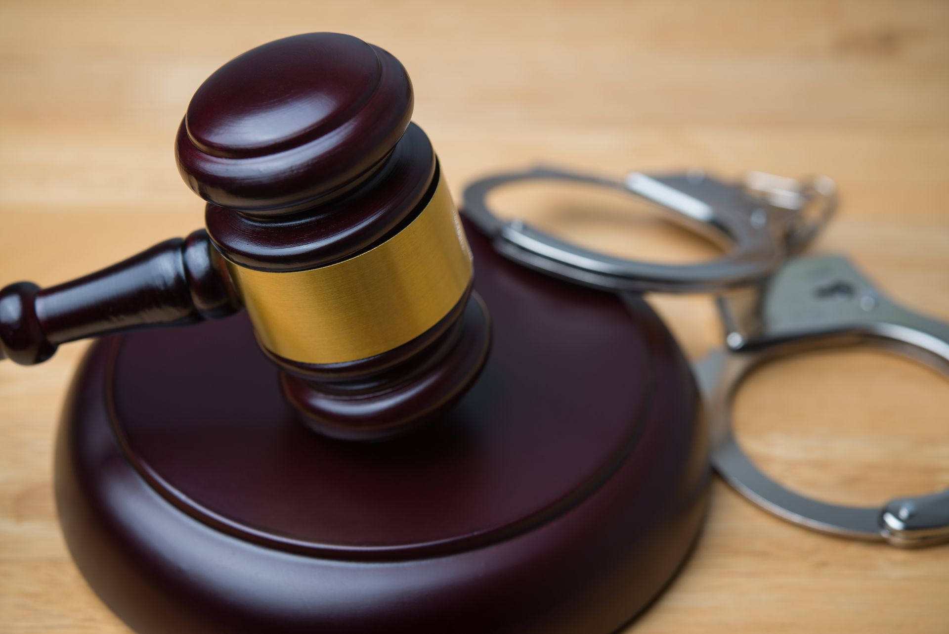 Gavel and handcuffs on wooden table symbolizing justice and criminal law enforcement.