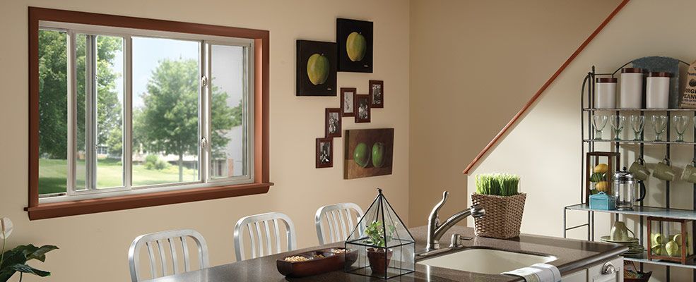 Kitchen interior with a window overlooking trees. A dark table has metal chairs. Art hangs on the wall.
