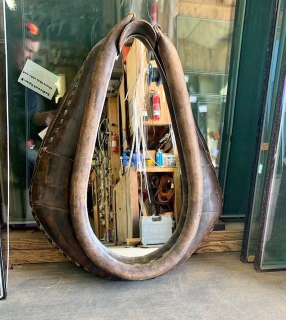 A large mirror with a brown leather frame is hanging on a wall