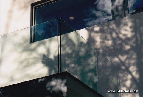 The shadow of a tree is cast on a glass railing.