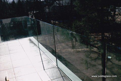 A glass railing on a balcony with trees in the background.