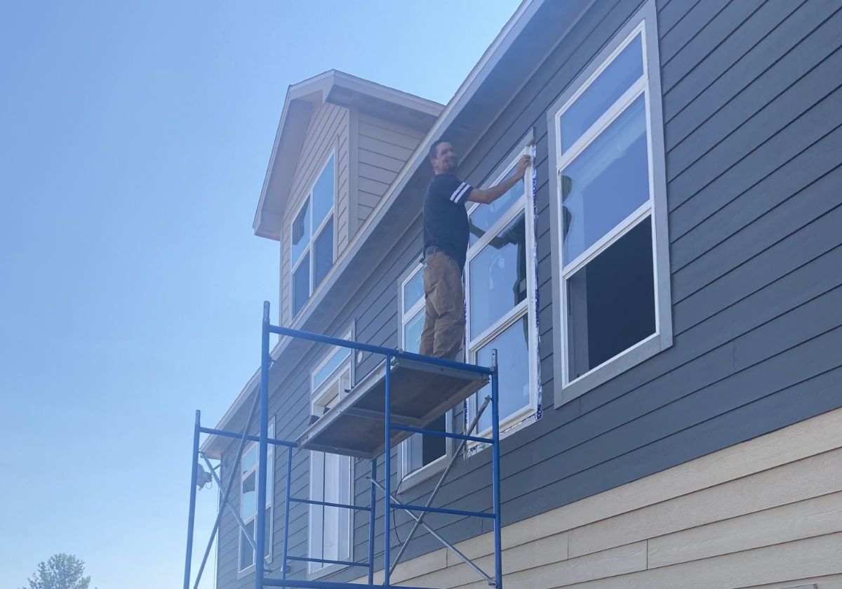 A man is standing on a scaffolding on the side of a house.