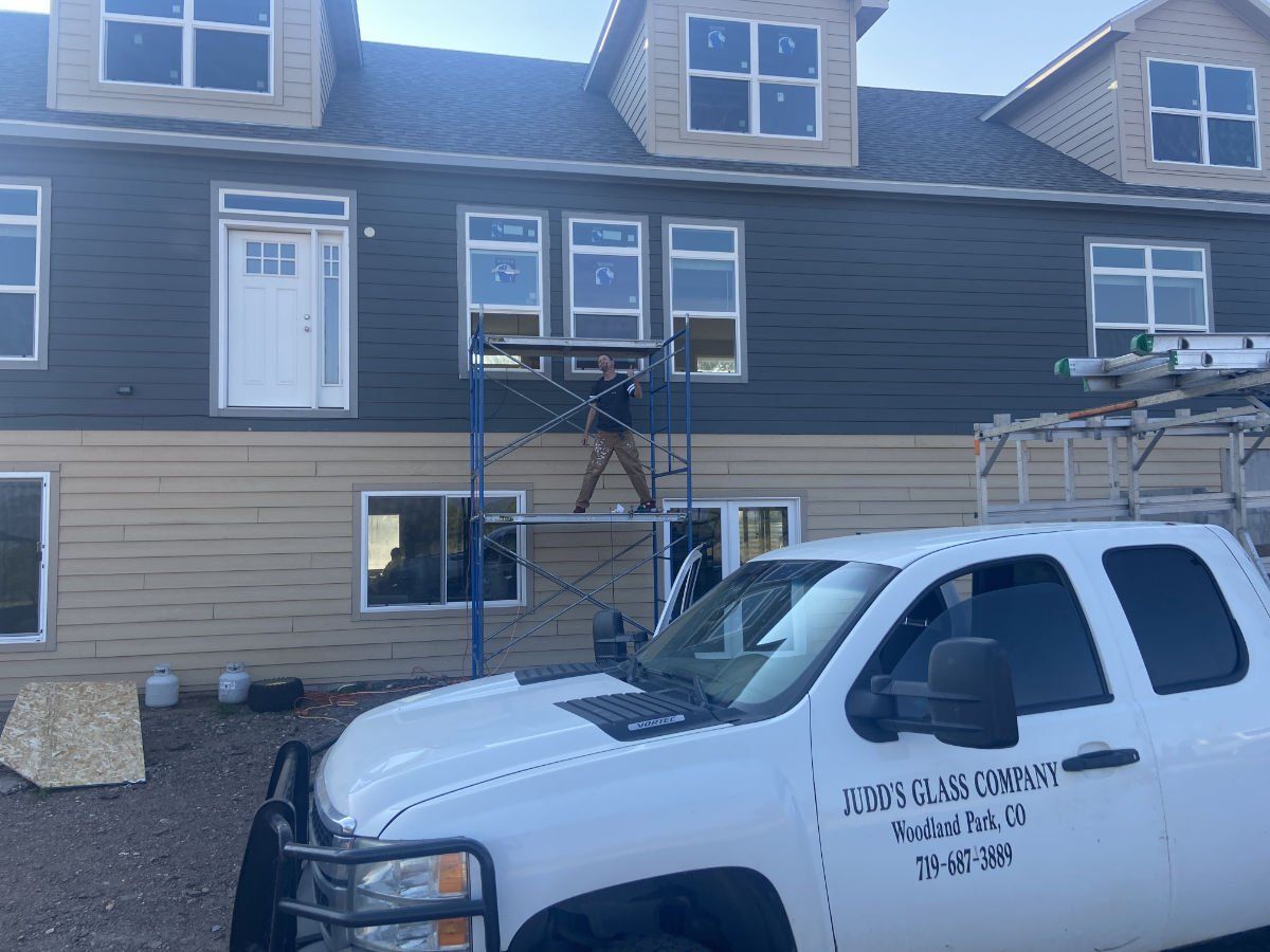 A white truck is parked in front of a house under construction.