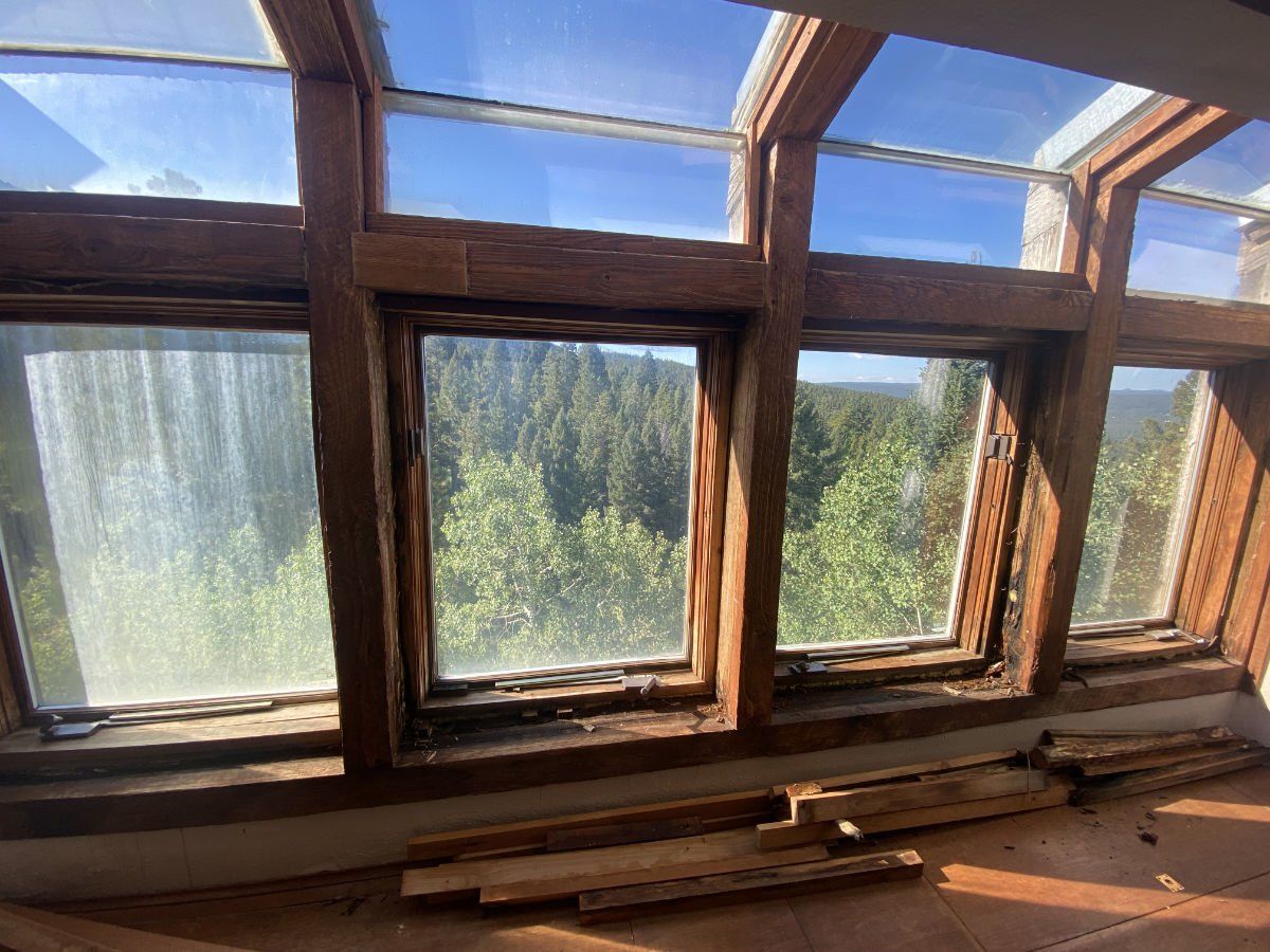 A room with a lot of windows and a view of a forest.