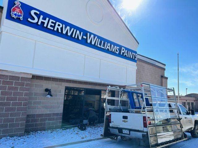 A truck is parked in front of a building that says sherwin-williams paints