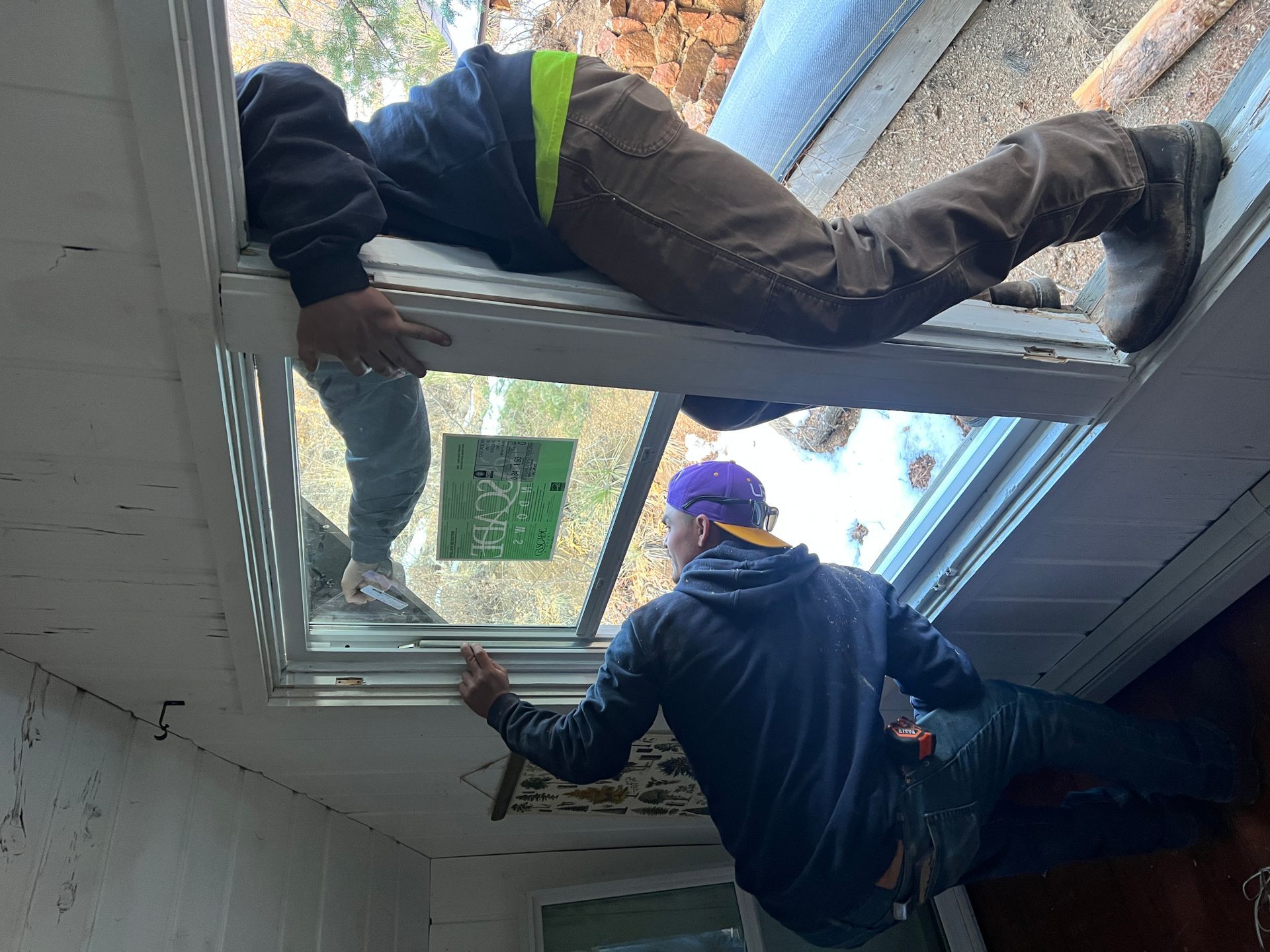 Two men are installing a window in a house.