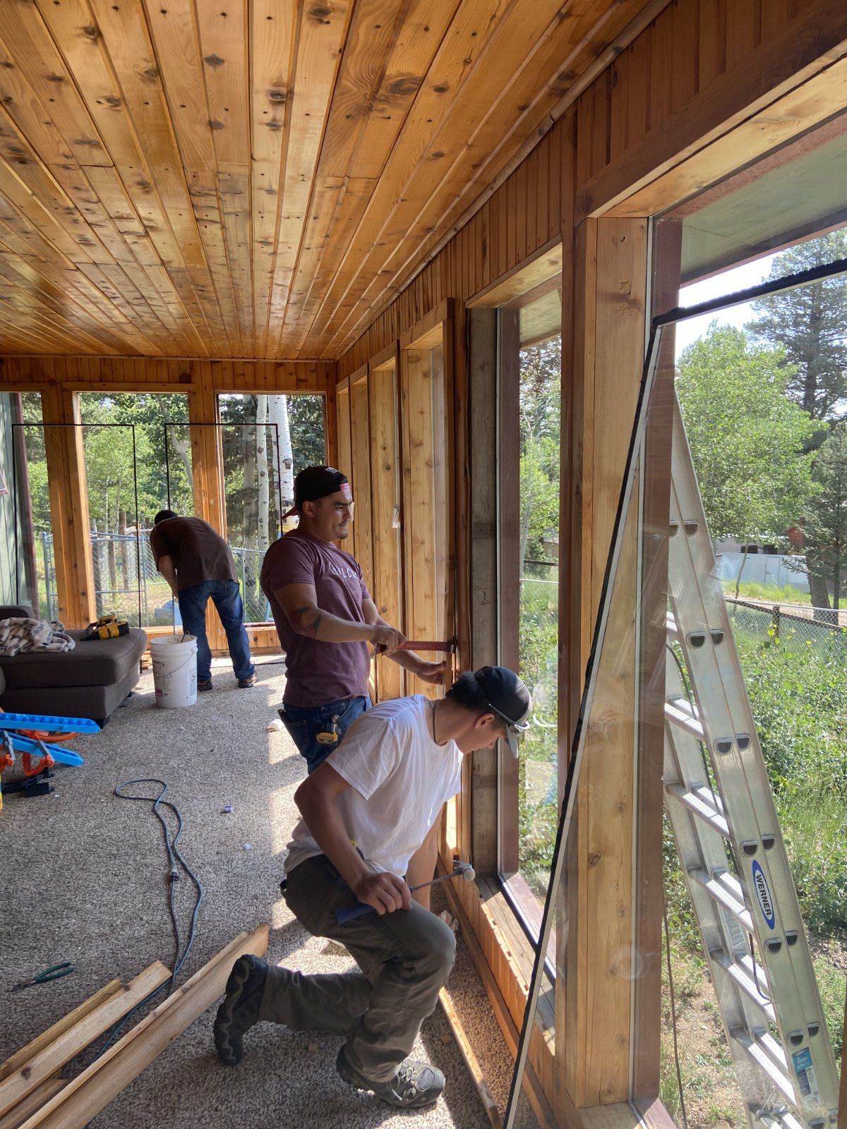 A group of men are working on a porch in a house.