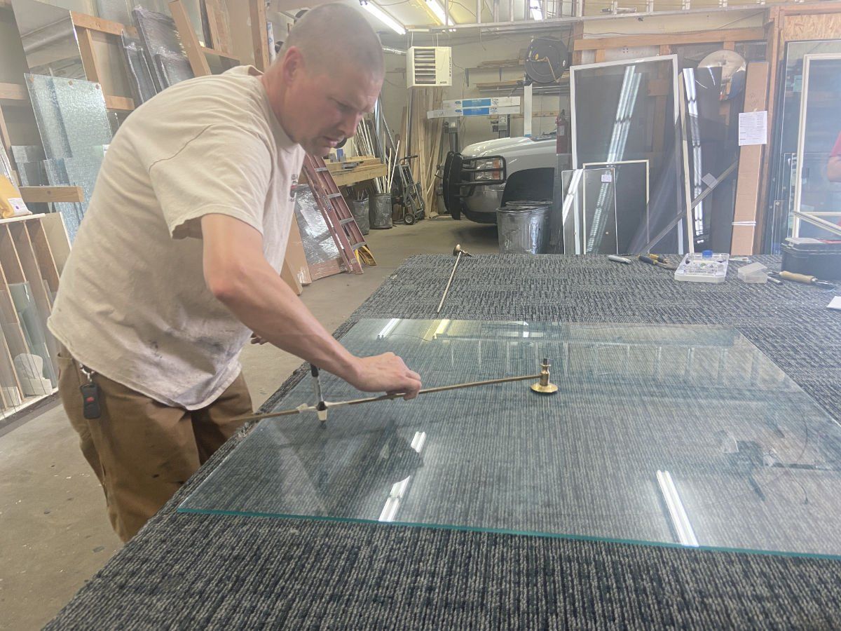 A man is cutting a piece of glass with a pair of scissors.