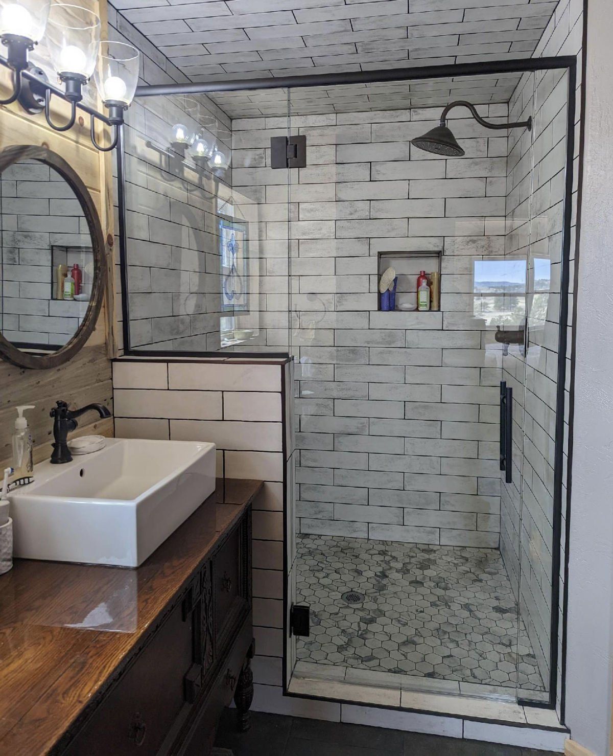 A bathroom with a sink , mirror , and walk in shower.