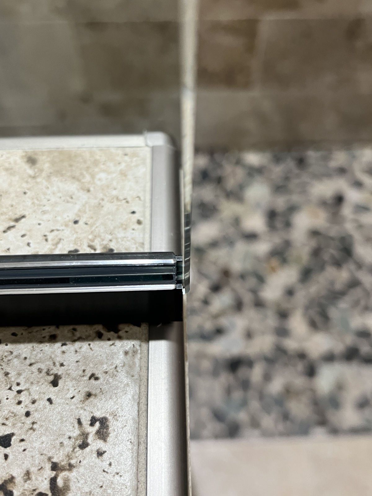 A close up of a glass door between two tiles in a bathroom.
