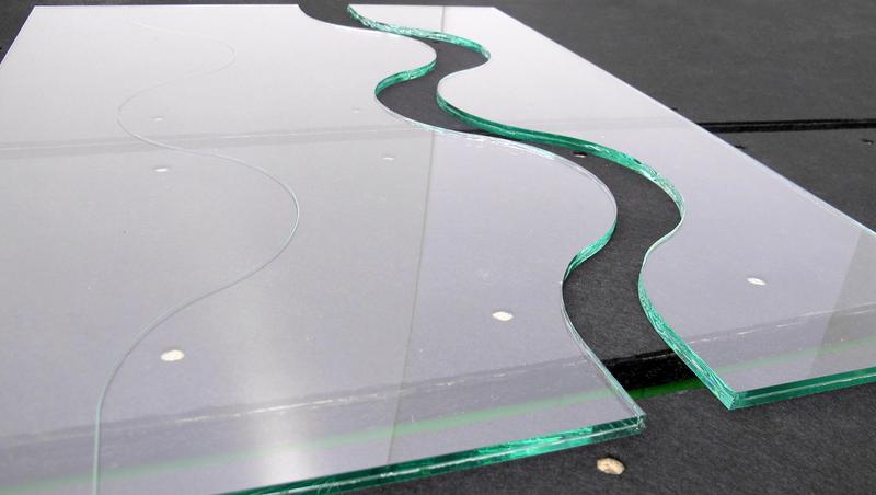 A piece of glass with a curved edge is sitting on a table.