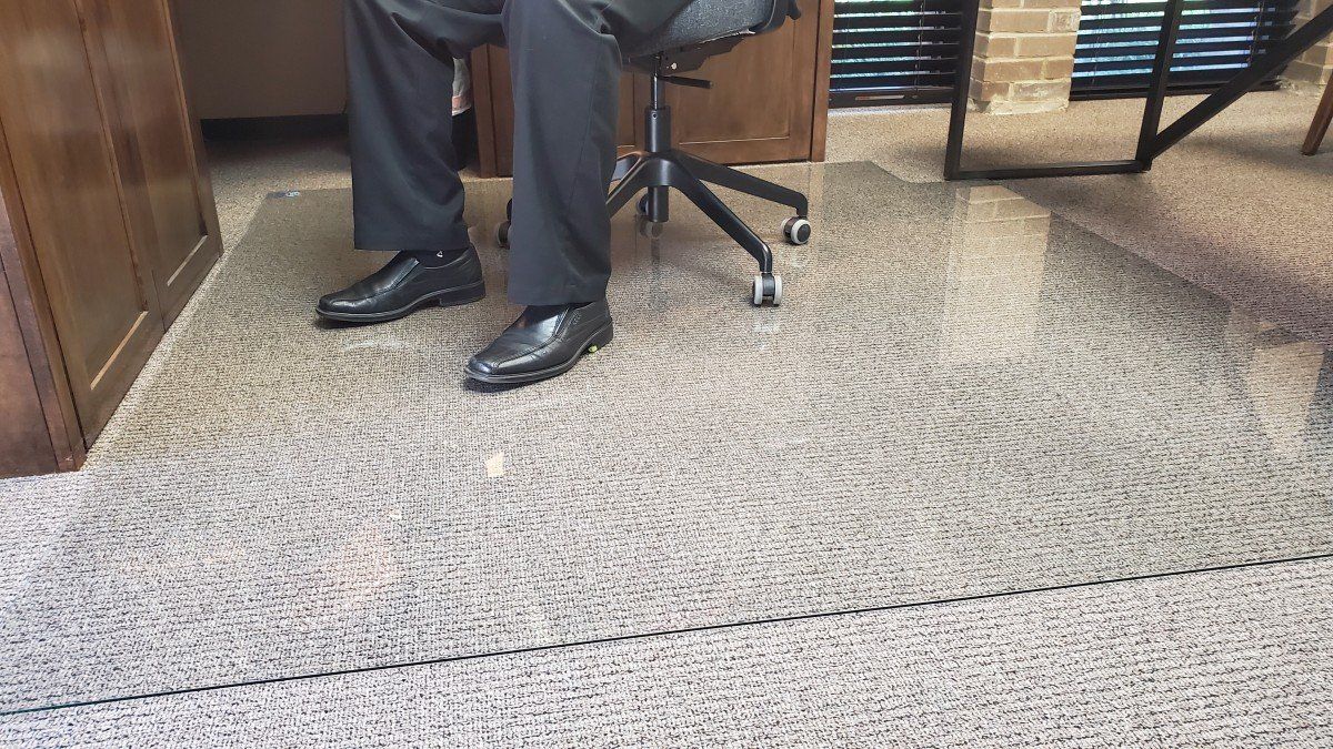 A man is sitting in an office chair on a carpeted floor.