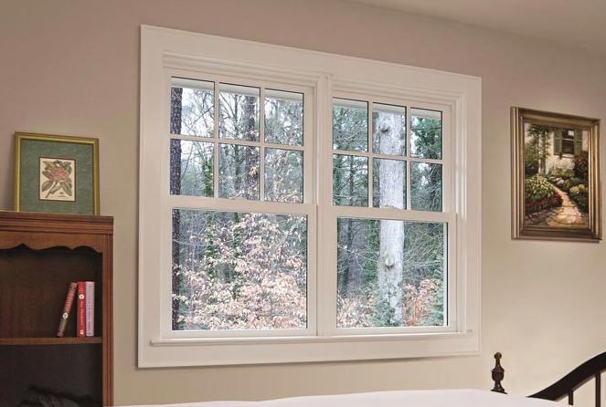 A bedroom with a large window and a bookshelf.
