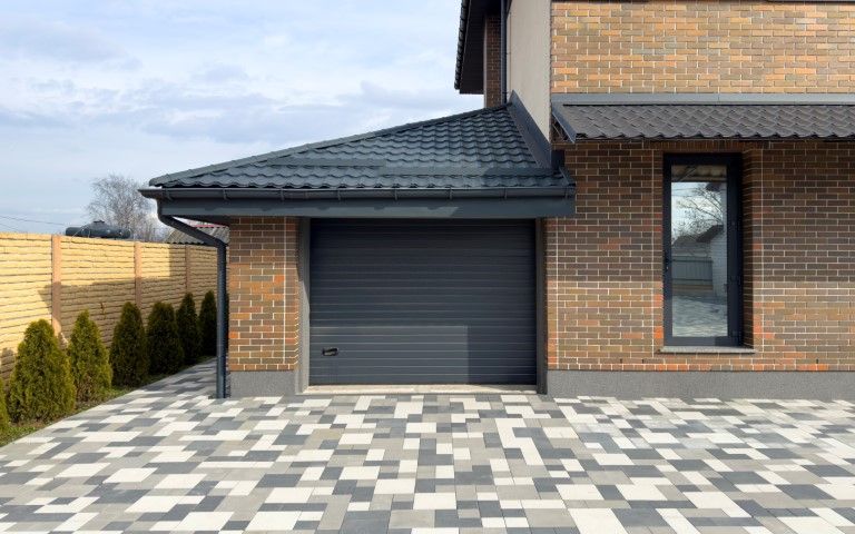 A brick house with a black garage door and a brick driveway.